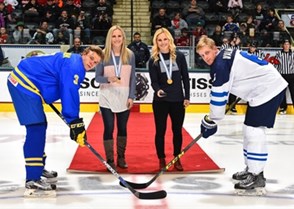 GRAND FORKS, NORTH DAKOTA - APRIL 24: Former University of North Dakota women's hockey alumni Monique Lamoureux and Jocelyn Lamoureux-Davidson present the ceremonial puck drop with Sweden's Jacob Cederholm #3 and Finland's Juuso Valimaki #6 during gold medal game action at the 2016 IIHF Ice Hockey U18 World Championship. (Photo by Matt Zambonin/HHOF-IIHF Images)

